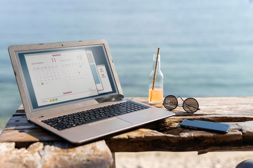 Laptop with business calendar open in sunshine with sea view behind Laptop with business calendar open in sunshine with sea view behind